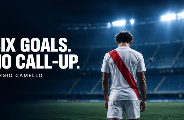 Football striker in a white shirt with a red sash standing alone in a floodlit stadium, illustrating the Sergio Camello Spain squad snub
